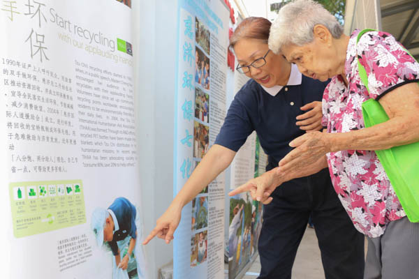 志工黄碹意引领吴亚容阿嬷（右）到看板区，仔细地为她讲解全球暖化所带来的灾害，以及“八分饱，两分施”，更教导阿嬷“清净在源头”的观念。摄 / 黄思妮